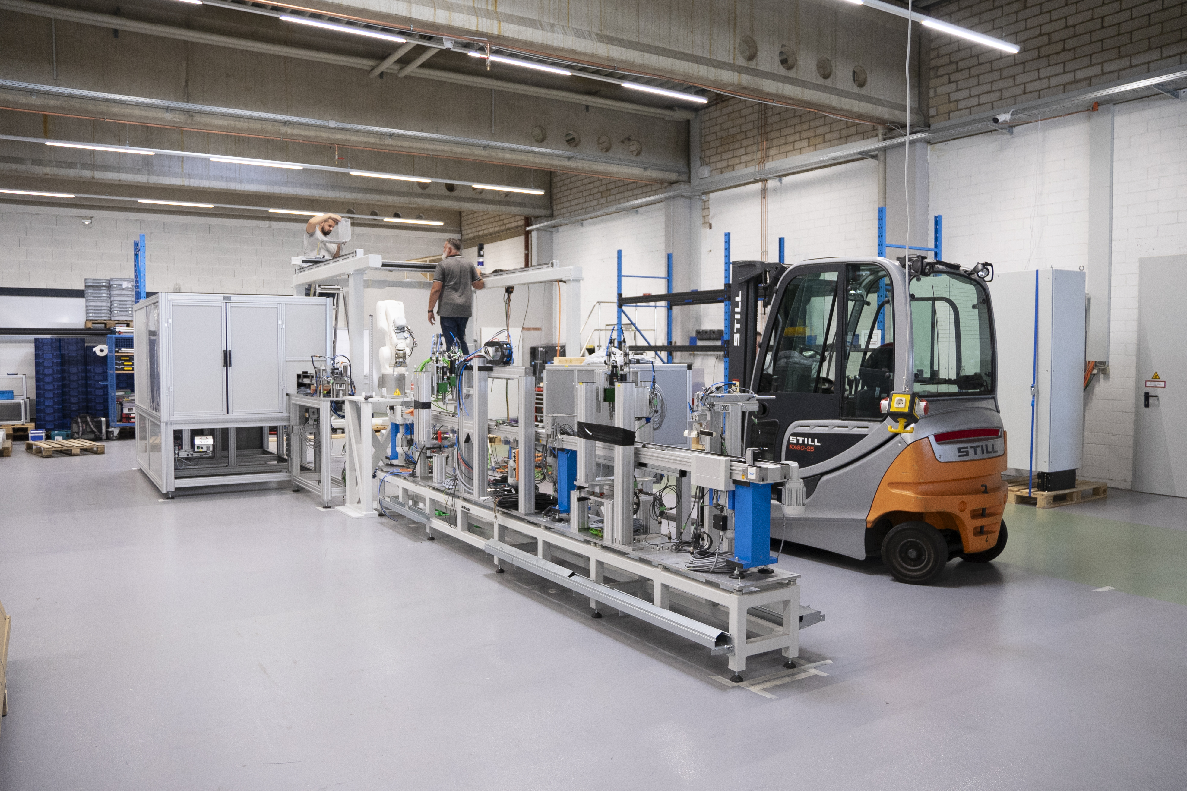 Das erste Stück der Maschine steht; dahinter ist ein Gabelstapler zu sehen