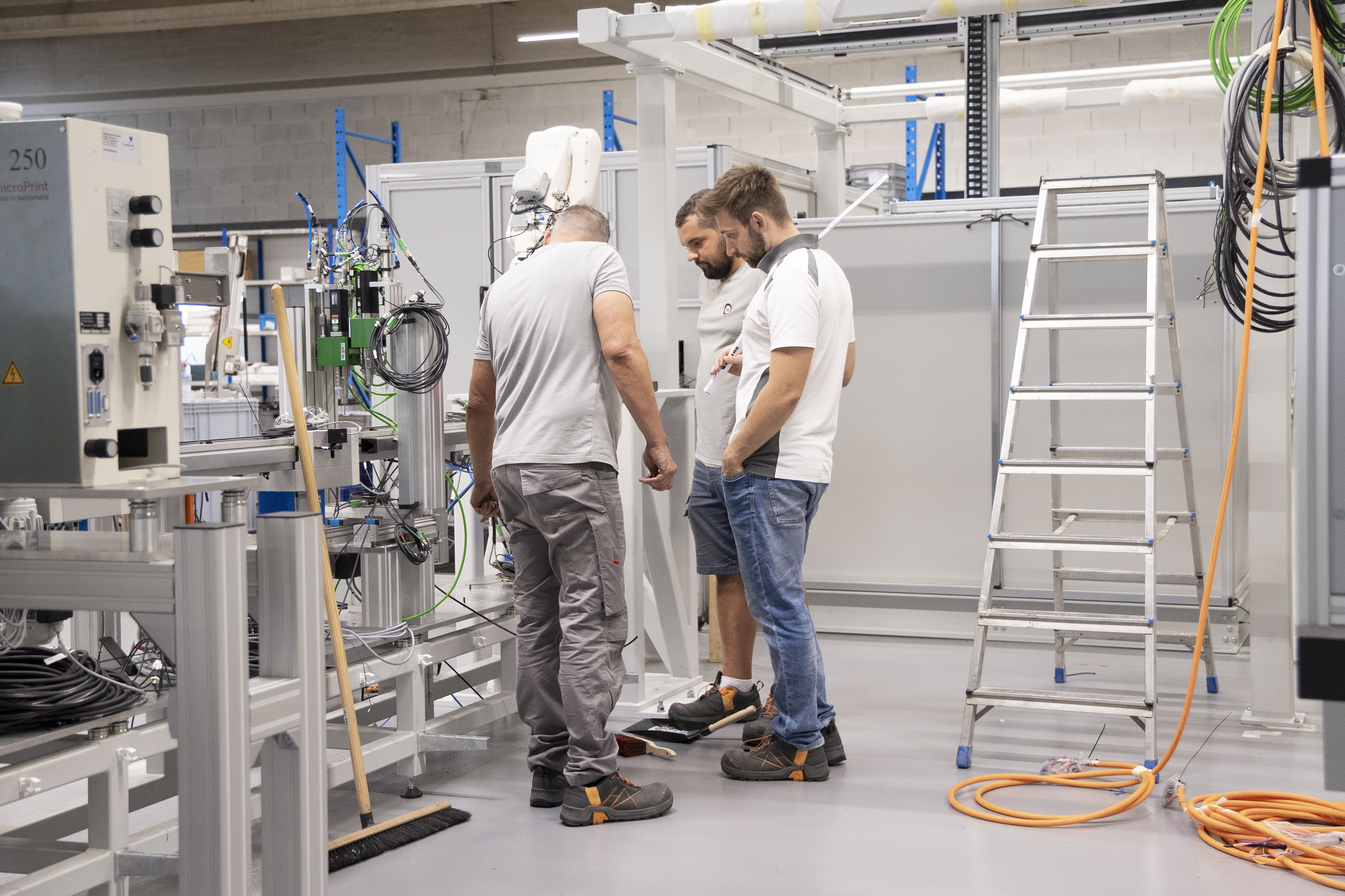 Drei MMTE-Mitarbeiter stehen zusammen in der halb aufgebauten Maschine